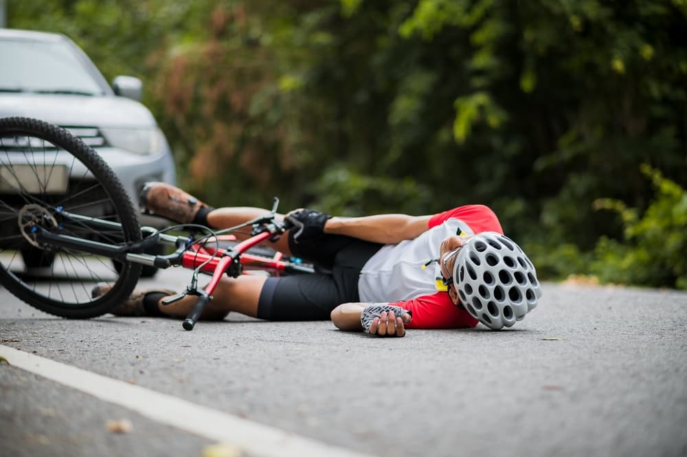 An Asian mountain biker was hit by a car on the road.